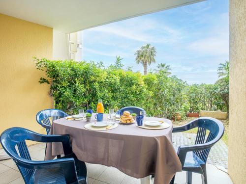 une table avec des chaises bleues assises sur une terrasse dans l'établissement Apartment Les Goelettes-6 by Interhome, à Saint Cyprien Plage