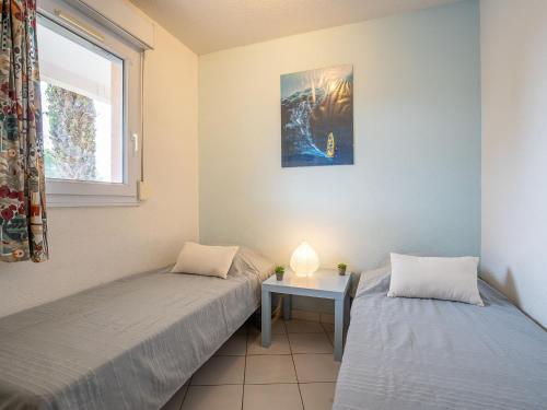 - 2 lits dans une chambre avec une table et une fenêtre dans l'établissement Apartment Les Goelettes-6 by Interhome, à Saint Cyprien Plage