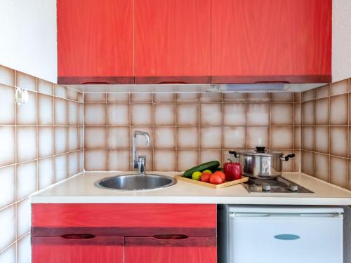 une cuisine avec des armoires rouges et un évier dans l'établissement Studio Le Lagon Bleu-1 by Interhome, au Grau-du-Roi