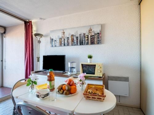 une table avec une assiette de fruits et un micro-ondes dans l'établissement Studio Le Lagon Bleu-1 by Interhome, au Grau-du-Roi