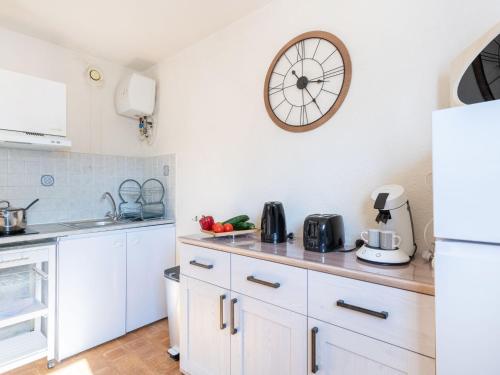 a kitchen with white cabinets and a clock on the wall at Apartment Les Sables d'Or-8 by Interhome in Le Grau-du-Roi