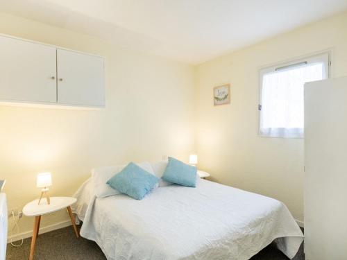 a bedroom with a white bed with blue pillows at Apartment Les Sables d'Or-8 by Interhome in Le Grau-du-Roi