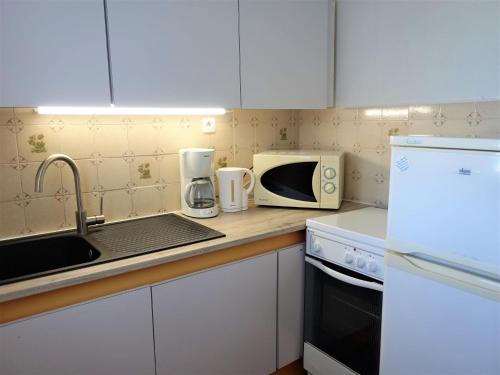 une cuisine avec un comptoir avec un évier et un micro-ondes dans l'établissement Apartment Le Grand Pavois by Interhome, au Barcarès