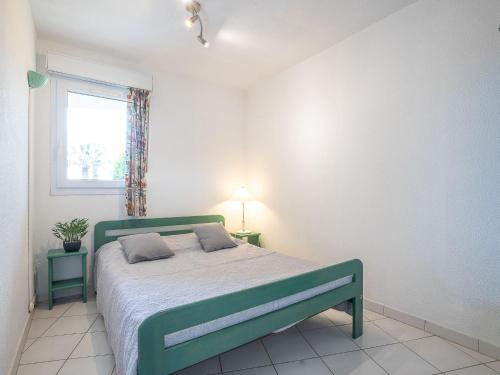 - un lit vert dans une chambre blanche dotée d'une fenêtre dans l'établissement Apartment Les Goelettes-8 by Interhome, à Saint Cyprien Plage