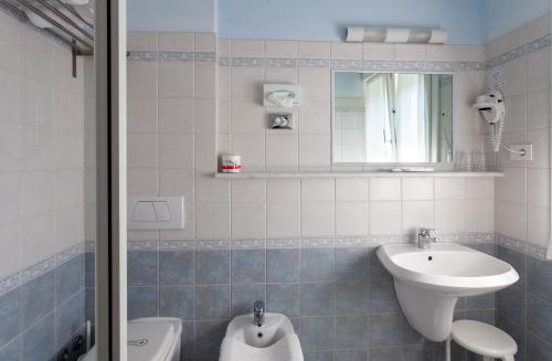 een badkamer met een wastafel, een toilet en een spiegel bij Hotel Tarabella in Forte dei Marmi