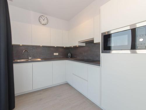 uma cozinha com armários brancos e um relógio na parede em Apartment Residentie Astrid-6 by Interhome em Bredene