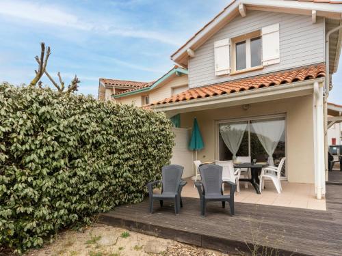 a house with a deck with chairs and a table at Holiday Home Le Hameau des Pêcheurs 1 by Interhome in Mimizan-Plage