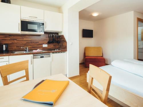 ラディスにあるApartment Ladis-8 by Interhomeのキッチン、ベッド1台、テーブルが備わる小さな客室です。