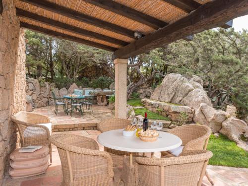 a patio with a table and chairs under a wooden pergola at Holiday Home Roccia di Volpe by Interhome in Porto Cervo