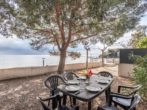 a table with chairs sitting next to the water at Holiday Home Polpu by Interhome in Sari Solenzara