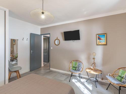 a bedroom with a bed and two chairs and a tv on the wall at Holiday Home Polpu by Interhome in Sari Solenzara