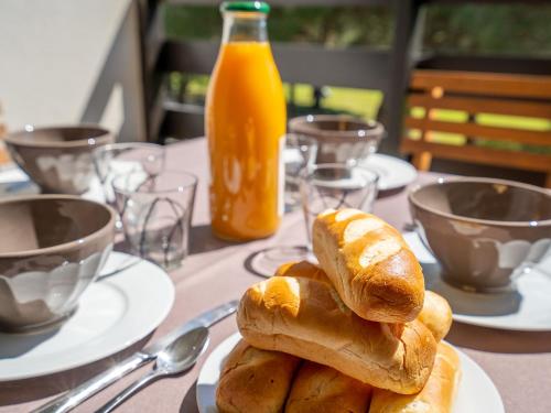 - une assiette de pain sur une table avec une bouteille de jus d'orange dans l'établissement Apartment Le Golf Clair-15 by Interhome, à Saint-Cyprien