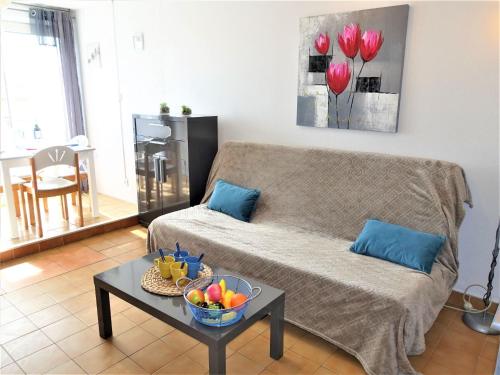 un salon avec un canapé et une table avec un bol de fruits dans l'établissement Apartment Les Maisons sur la Plage-9 by Interhome, à Narbonne-Plage