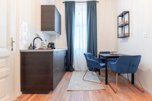 eine Küche mit einem Tisch und 2 blauen Stühlen in der Unterkunft City Appartement WAGRAM am Hauptbahnhof in Sankt Pölten