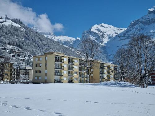 a building in the snow with mountains in the background at Apartment Erlenrain Wohnung 911 by Interhome in Engelberg