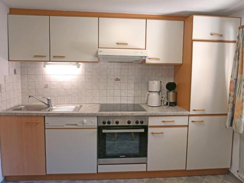 una cocina con armarios blancos y fregadero en Apartment Alpenhof-3 by Interhome, en Kappl