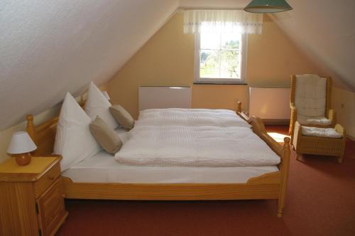 a bedroom with a bed and a chair and a window at Ferienhaus Hummel-Nest in Laußnitz
