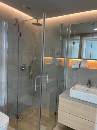 a bathroom with a shower and a sink at PINEA Apartments Pobierowo z niesamowitym widokiem na morze oraz jacuzzi w wybranych apartamentach in Pobierowo