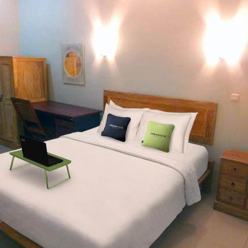 a bedroom with a large bed with a laptop on it at Urbanview Hotel Wayan Mansion in Denpasar