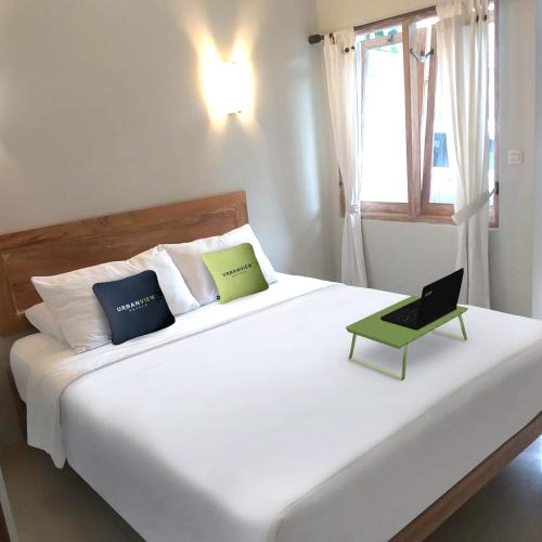 1 dormitorio con cama blanca y ordenador portátil en Urbanview Hotel Wayan Mansion, en Denpasar