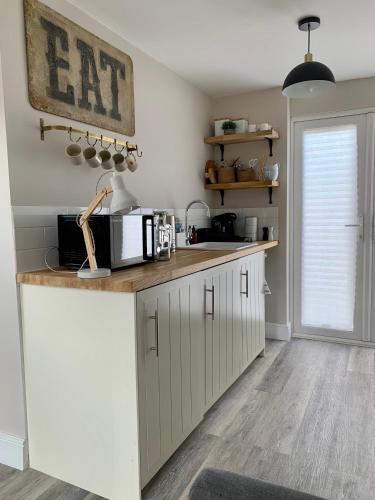a kitchen with white cabinets and a counter top at The Nest in Sway