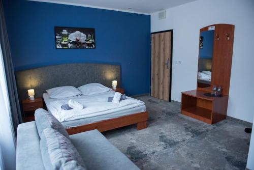 a blue bedroom with a bed and a couch at Hotel Paradiso in Suchedniów