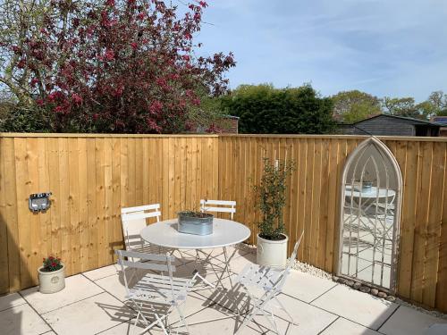 a patio with a table and chairs and a fence at The Nest in Sway