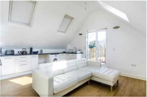 a white living room with a white couch and a kitchen at 2-Bed Loft Apartment for 5ppl with private parking in Beckenham