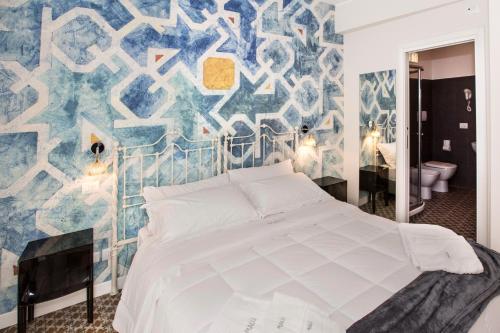 a bedroom with a white bed and a blue and white wall at Malù Suites in Messina