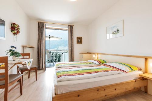 Schlafzimmer mit einem Bett, einem Tisch und einem Fenster in der Unterkunft Appartement Florian in Kaltern
