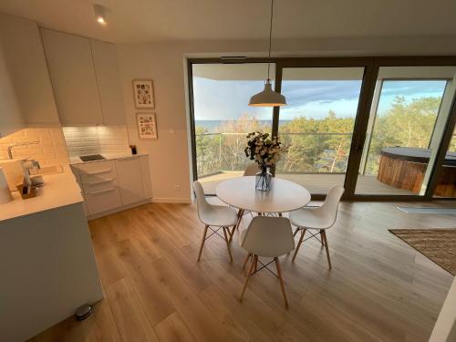 a kitchen and dining room with a table and chairs at PINEA Apartments Pobierowo z niesamowitym widokiem na morze oraz jacuzzi w wybranych apartamentach in Pobierowo