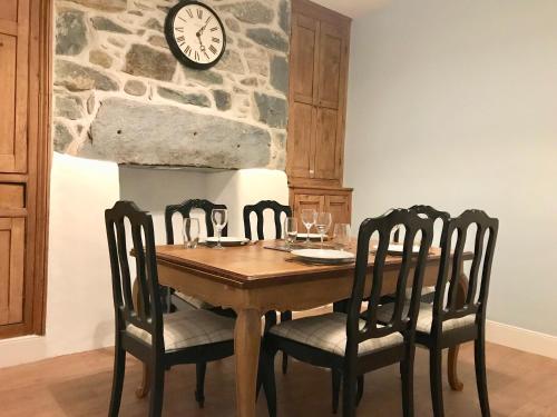 mesa de comedor con sillas y reloj en la pared en Bro Arran, en Dolgellau