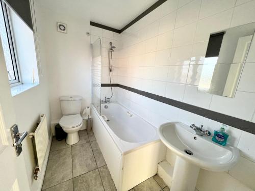 a bathroom with a tub and a sink and a toilet at Spacious 3-Bedroom house with 5 beds and sofa-bed in Manchester