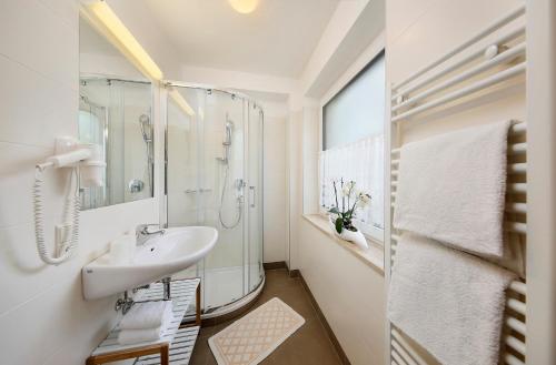 a white bathroom with a sink and a shower at Pension Siller in Lagundo