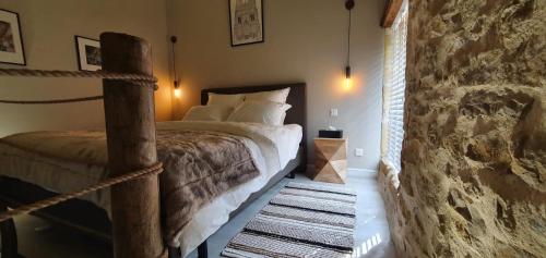1 dormitorio con cama y pared de piedra en La Jonquette, en Francheval