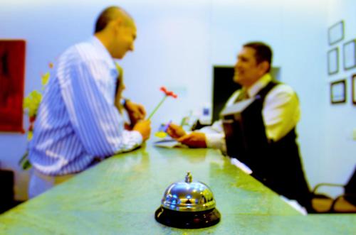 two men standing around a table with a hat on it at Hotel Pinares Plaza in Pereira