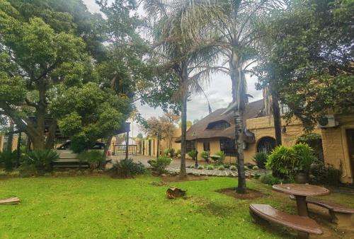 a building with a yard with benches and trees at Camelot Guesthouse in Newcastle
