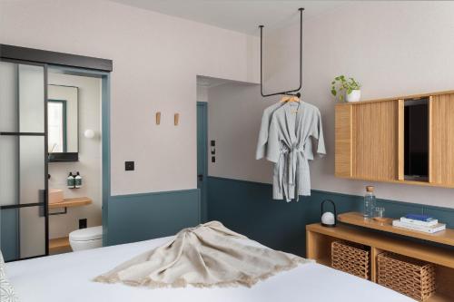 a room with a bed and a robe hanging on the wall at Inhabit Queen's Gardens, a Member of Design Hotels in London