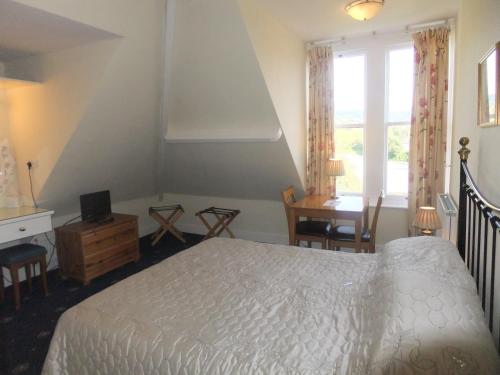 a bedroom with a bed and a desk and a window at Elgin Villa in Bath