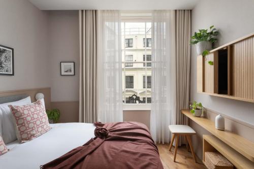 a bedroom with a bed and a window at Inhabit Queen's Gardens, a Member of Design Hotels in London