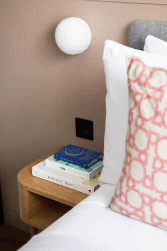 a bed with a table with two books on it at Inhabit Queen's Gardens, a Member of Design Hotels in London