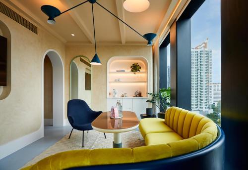 a living room with a yellow couch and a table at The Standard, Bangkok Mahanakhon in Bangkok