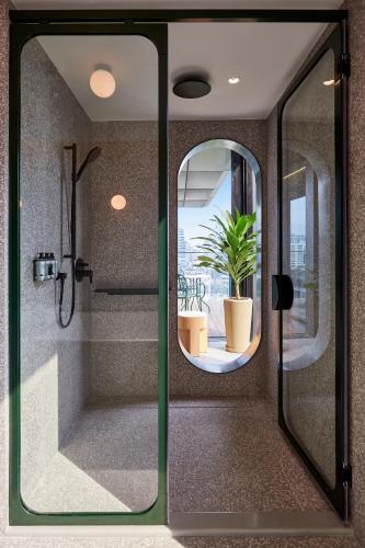a shower with a glass door with a potted plant at The Standard, Bangkok Mahanakhon in Bangkok