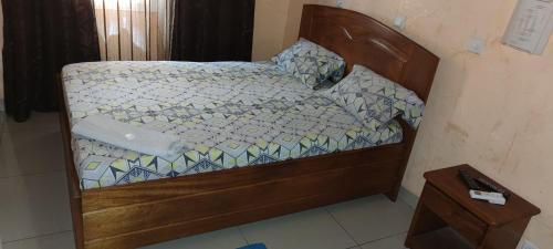 a small bed with a wooden frame in a room at HOTEL-LE-PARISIEN in Brazzaville