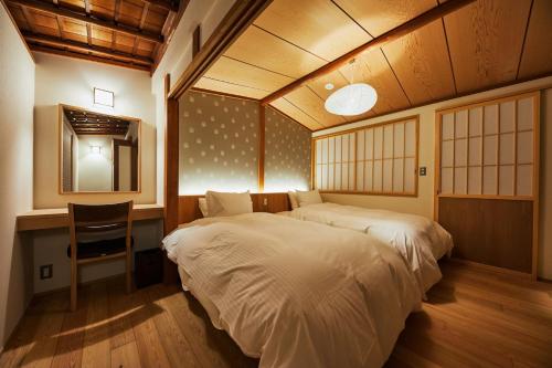 a bedroom with two beds and a desk and a table at Gion Shirakawa no Yado in Kyoto