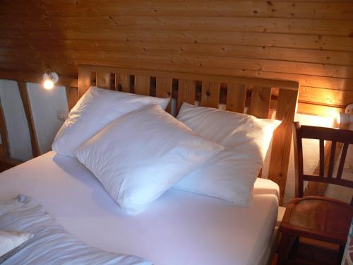 1 cama con almohadas blancas y pared de madera en GITE Le Bosquet en Chépy