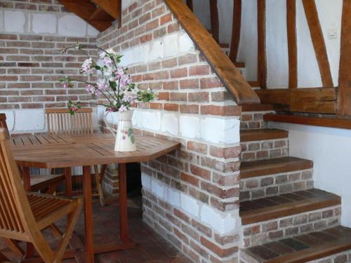 una pared de ladrillo con una mesa y un jarrón de flores en GITE Le Bosquet en Chépy