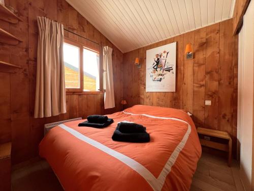 ヴァル・トランスにあるRésidence Eskivalのベッドルーム1室(オレンジ色のベッド1台、黒い枕2つ付)