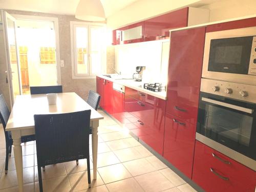 uma cozinha com armários vermelhos, uma mesa e um fogão em Le Laurier em Vouvray