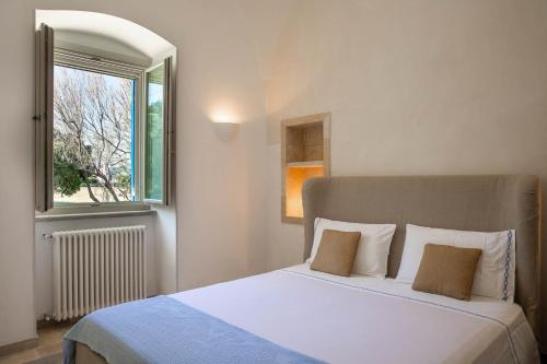 a bedroom with a white bed and a window at La Porta del Mare in Villanova di Ostuni